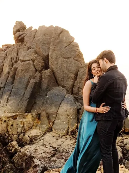 An intimate embrace on the rugged rocks of a Goan beach. This shot highlights the contrast between the soft, romantic moment and the wild, natural setting.