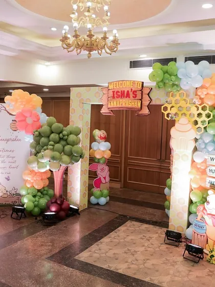 The entrance to a Winnie the Pooh themed Annaprashan ceremony. The decor includes a custom backdrop, balloon trees, and a light up photo frame for a personal touch.