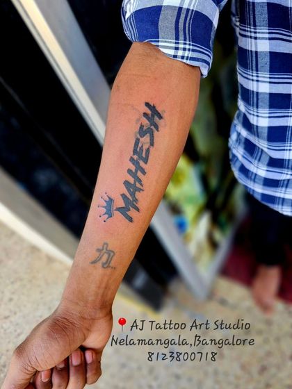 A "MAHESH" name tattoo in a custom font, covering up a smaller, older tattoo.