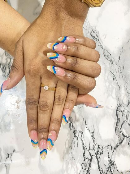 Another perspective of the playful, abstract nail art. This view highlights the careful placement of the pearl accents that complement the wavy blue and yellow lines.
