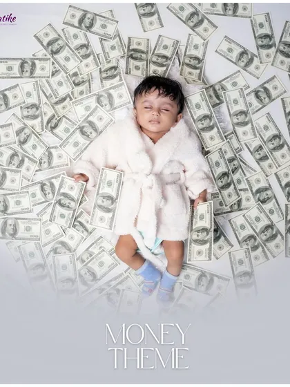 Dreaming of riches. This creative 'Money Theme' shot features a baby in a bathrobe sleeping on a bed of hundred-dollar bills.