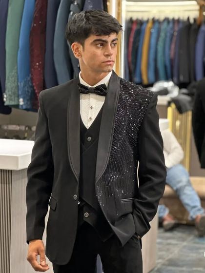 A young client trying on a modern black tuxedo with an asymmetrical sequined lapel. This design is perfect for a prom, farewell, or the stylish younger wedding guest.