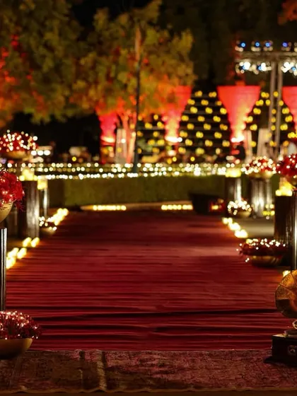 The grand entrance path, lined with candles and stands holding bowls of red roses, leading towards the majestically lit Umaid Bhawan Palace.