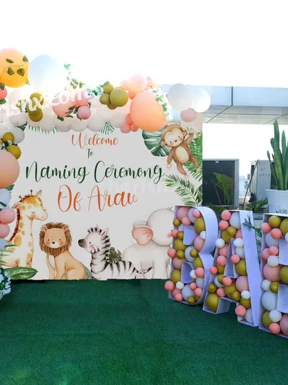 A charming naming ceremony decoration with a gentle jungle animal theme. The outdoor setup includes a personalized 'Welcome to Naming Ceremony' backdrop and 'BABY' marquee letters filled with balloons.