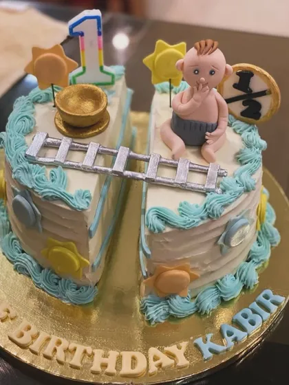 A creative half-birthday cake for Kabir. The cake is split in two, connected by a ladder, with a baby figure celebrating the six-month milestone.