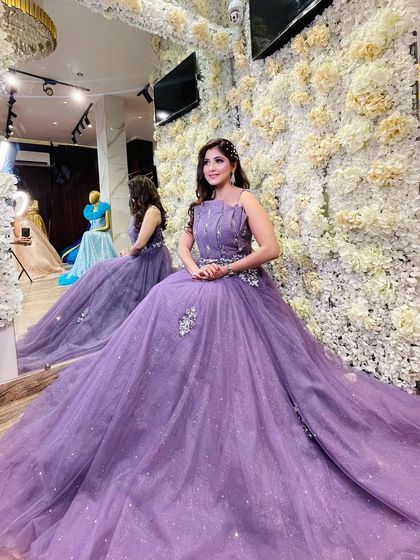 A client seated in a lovely lavender evening gown. The dress features a sparkling, embellished bodice and a soft, flowing tulle skirt, perfect for a reception or sangeet event.