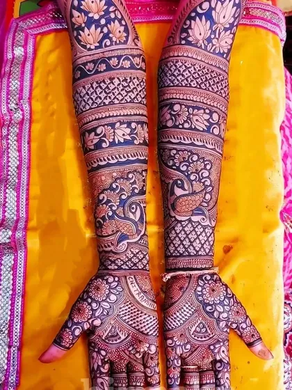 A beautiful design with peacocks and lotuses, set against a bright yellow background that makes the henna pop.