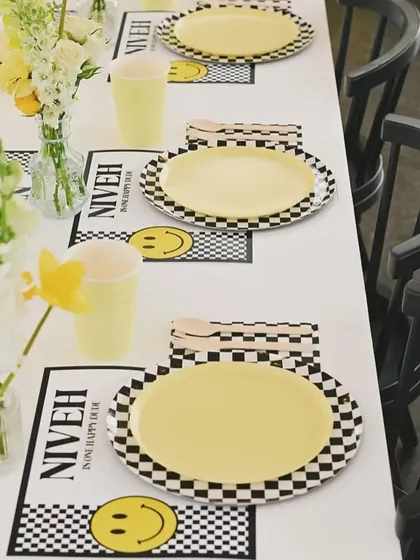 A cheerful 'Happy Dude' sunshine-themed first birthday. The table setting features smiley face placemats and a black, white, and yellow color scheme.