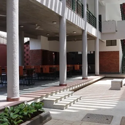 A semi-open breakout space at the Karigar Centre in Hosur. Supported by simple columns, this area provides a naturally ventilated and shaded environment for employees to relax. The design prioritizes comfort and community, integrating functional spaces with the natural climate.