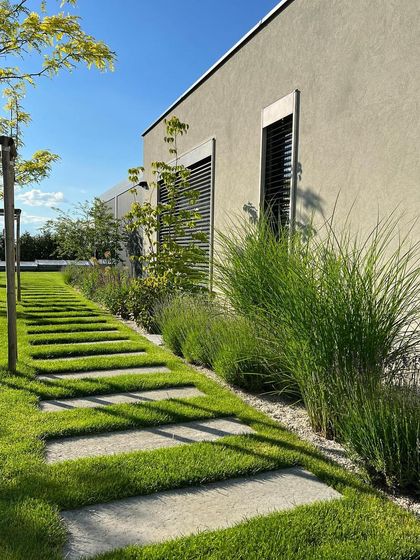 A long pathway of stepping stones set into the lawn runs parallel to the house. This design creates a strong leading line and a sense of order, complemented by a border of tall grasses.