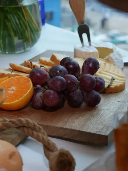 A close-up of a simple yet elegant cheese board, focusing on the natural beauty of fresh grapes, crackers, and a wheel of brie, ready to be enjoyed.