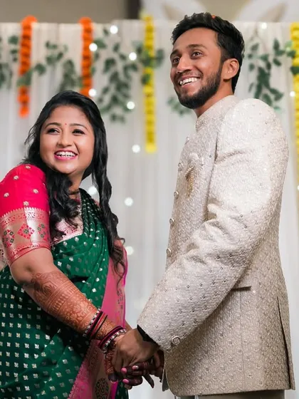 A happy couple holding hands and smiling during their engagement ceremony.