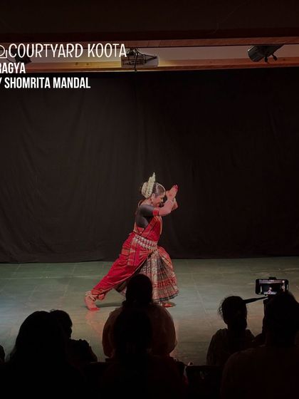 A captivating Odissi performance of 'Pragya' by Shomrita Mandal. The dancer's pose, set against the dark stage, highlights the sculptural beauty and precision of this classical dance form.