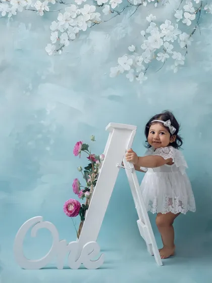 Standing tall at one. Using a large "One" prop and a beautiful floral backdrop, this shot celebrates a major milestone in a baby's life. It's a classic portrait for any first birthday album.