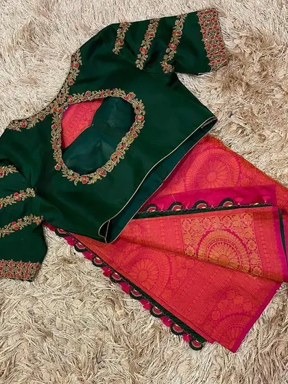 A classic festive combination of a bottle green hand-embroidered blouse with a bright pink silk saree, finished with a traditional black krosha tassel border.