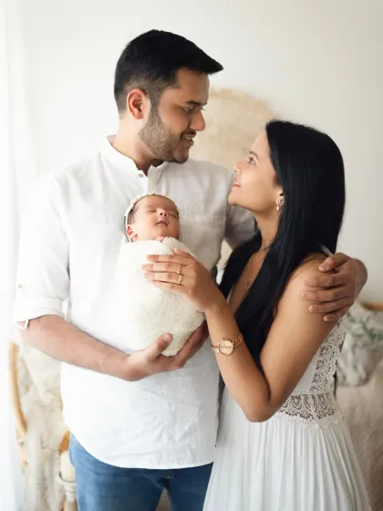 A beautiful moment between a new mother and father as they gaze at each other while holding their newborn. This is a perfect example of a lifestyle candid photoshoot.