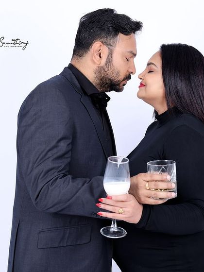A sophisticated couple portrait with the couple sharing a toast. Their elegant black attire and happy expressions create a celebratory and modern maternity photo.