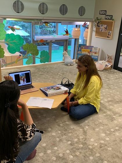 An educator uses a laptop to share video documentation with parents during a conference. This allows parents to see their child's learning process in action and provides a richer context for our discussions.