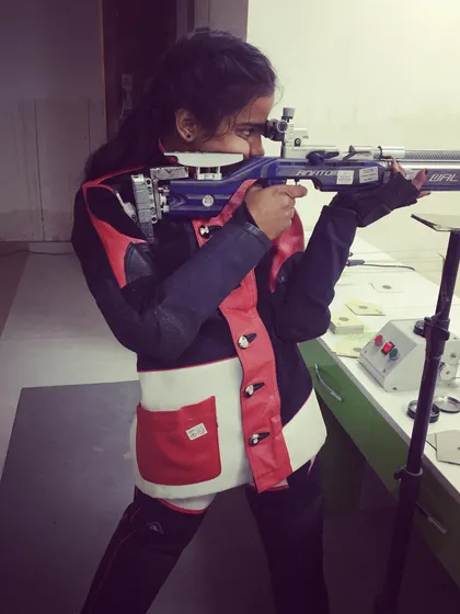 A young female shooter takes aim with her Walther air rifle, showing great concentration and proper technique.