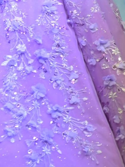 The delicate branches and blossoms embroidered onto this lavender gown are inspired by the beauty of a garden in full bloom.