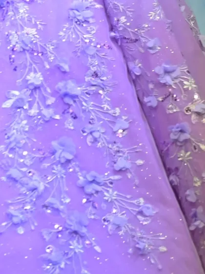 The delicate branches and blossoms embroidered onto this lavender gown are inspired by the beauty of a garden in full bloom.