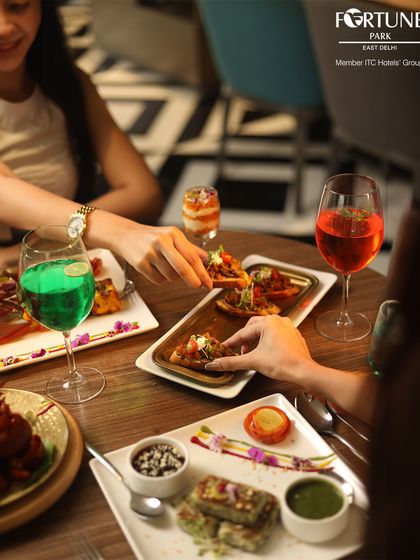 A shared moment over appetizers and colorful drinks. The artful plating and vibrant colors of the food and beverages make for an elegant dining experience.