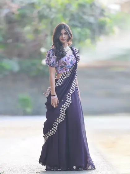 A full-length shot of a different half-saree from the same collaboration. This one features a dark purple skirt and a floral-printed blouse, showing a different style.