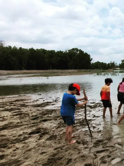 Armed with sticks and curiosity, the children explore the muddy edges of the lake. This is unstructured, child-led exploration at its best, where they learn about the properties of different materials and work together to navigate the terrain.