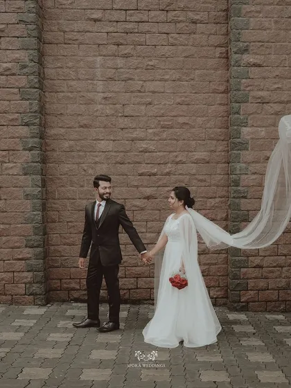 The couple walking hand-in-hand against a brick wall, the bride's veil flowing in the wind for a touch of romantic drama.