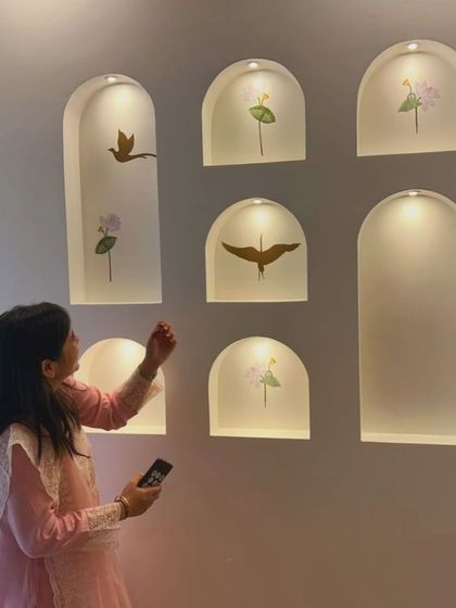 A candid moment captured as my client admires the newly finished accent wall in her living room. The wall features backlit niches with delicate, artistic decals, creating a personal and beautiful focal point.