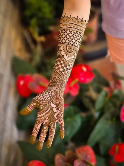 A single arm shot of a lovely bridal design, with red flowers in the background.