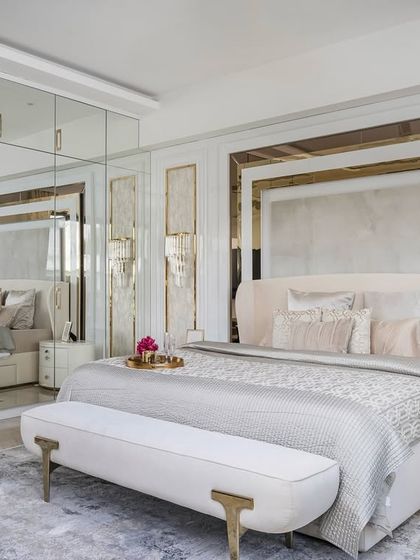 In this master bedroom, we used mirrored wardrobes to expand the sense of space. Soft curves in the furniture and layered paneling with gold accents around the bed create a plush, glamorous retreat that is a signature of our style.