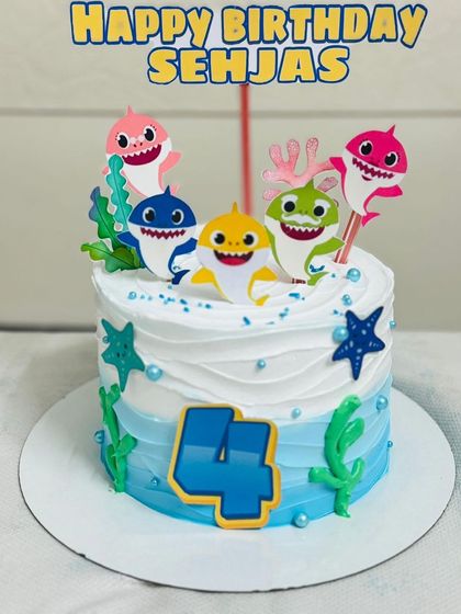 A vibrant Baby Shark themed cake for a 4th birthday, complete with the whole shark family.