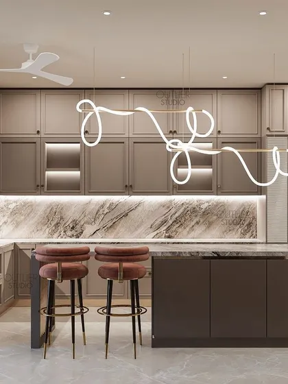 Another angle of the gourmet kitchen, highlighting the breakfast bar with stylish pink stools and the beautiful contrast between the neutral cabinets and the veined marble countertops.