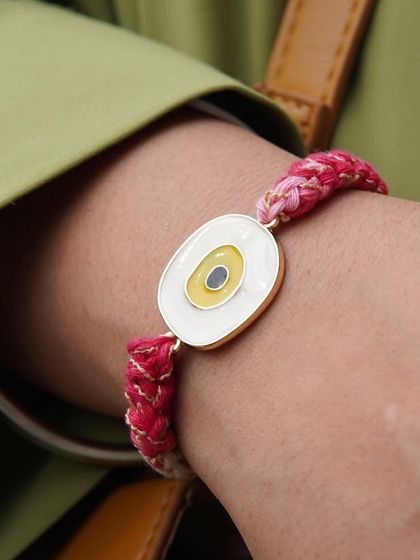 The yellow Evil Eye Rakhi worn on the wrist. It's perfect for sisters too!