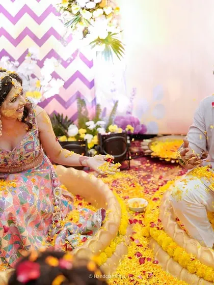 A playful moment as the couple is showered with turmeric and flower petals. The custom-designed seating bowls add a unique and practical element to the ceremony.