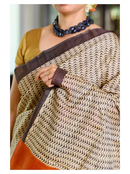 A close-up detail shot of the handloom saree, focusing on the fabric's texture, the border, and the necklace.