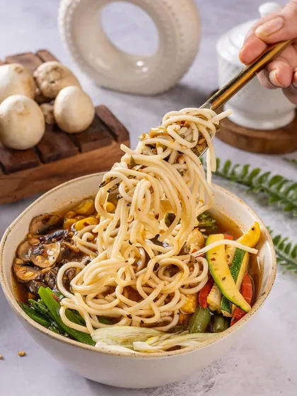 A comforting bowl of noodle soup. The action of lifting the noodles with a fork creates a sense of movement and makes you imagine taking the first slurp.