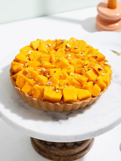 Our magical Mango Tart, with a crisp pastry shell filled with cream and piled high with fresh, sweet mangoes.