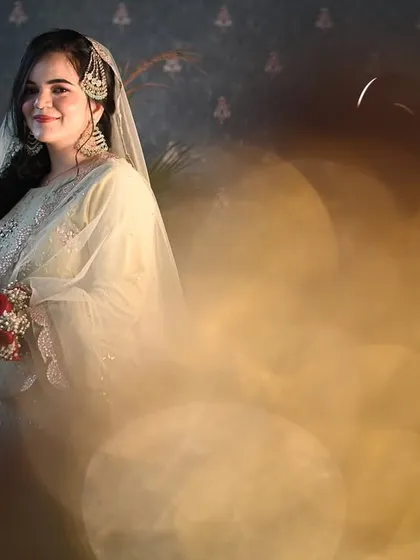 A bride's serene smile, captured through a dreamy, golden bokeh effect. This artistic portrait highlights her bridal glow and the magical atmosphere of her wedding day.