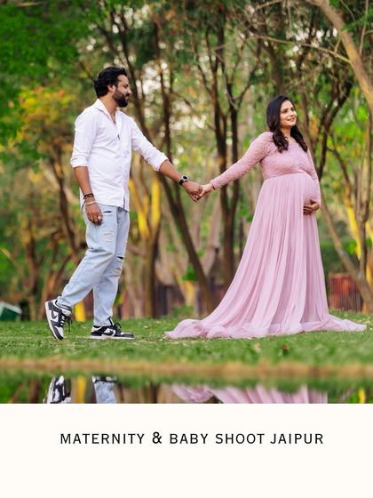 A romantic outdoor photo of a couple walking hand-in-hand by a reflective pond. The image captures a quiet moment of connection during their pregnancy journey.