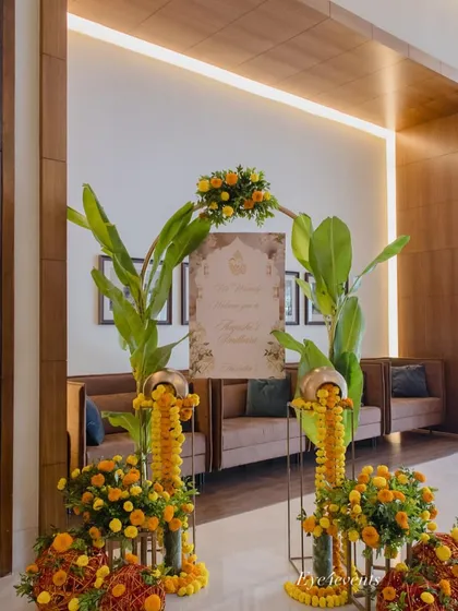 This is a traditional and warm welcome entrance I designed for a special event. It features arrangements of bright yellow and orange marigolds, large banana leaves, and traditional brass pots, creating an inviting and culturally rich first impression for guests.