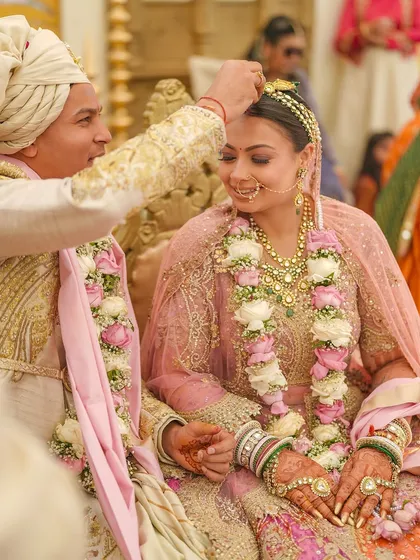 Another shot from the ceremony, showing the couple's coordinated floral garlands and their shared moment of happiness.