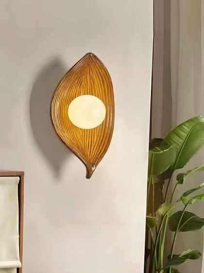 A nature-inspired wall light in the shape of a leaf. The light glows from the center, creating a soft, organic feel.