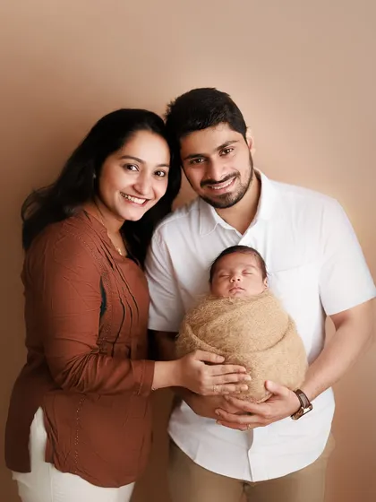The sweetness of a new family. This classic studio portrait captures the proud smiles of the new parents as they hold their precious, sleeping baby.
