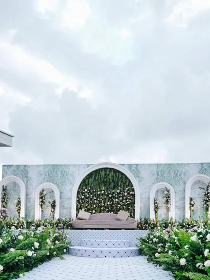 For the modern couple, we craft chic and sophisticated backdrops that speak to their style. This reception stage features a clean, marble-effect wall with integrated floral arches, creating a look of timeless elegance and contemporary design.