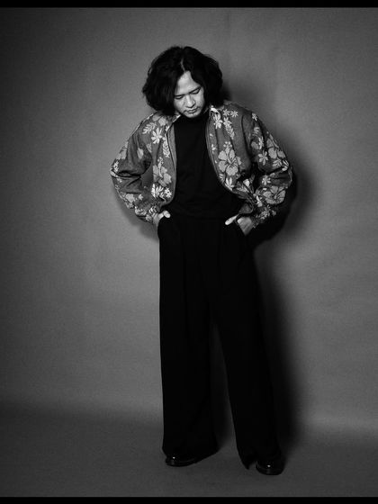 Taba Chake in a moment of introspection. The grey background and soft lighting create a contemplative and soulful mood.