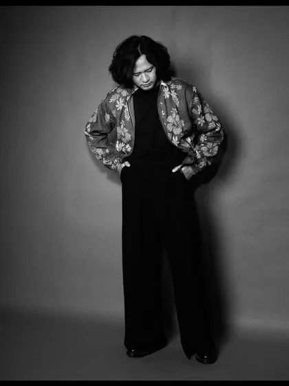 Taba Chake in a moment of introspection. The grey background and soft lighting create a contemplative and soulful mood.