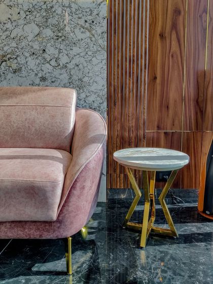A composition of materials in Mr. Siraj's office, showing the contrast between a soft pink sofa, a dark marble accent wall, and vertically grooved wood paneling. This demonstrates our approach to material layering.