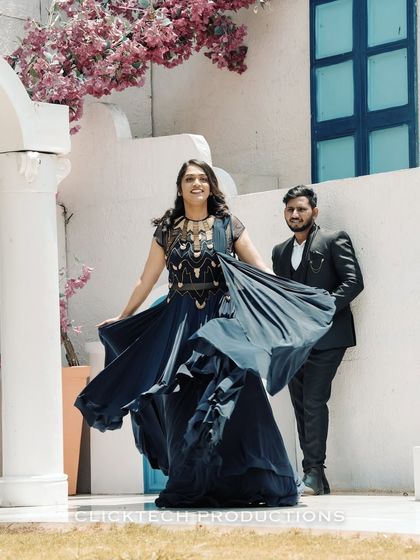 A playful moment captured at a picturesque outdoor set, with the bride twirling in her navy blue gown against a white, European-style building.